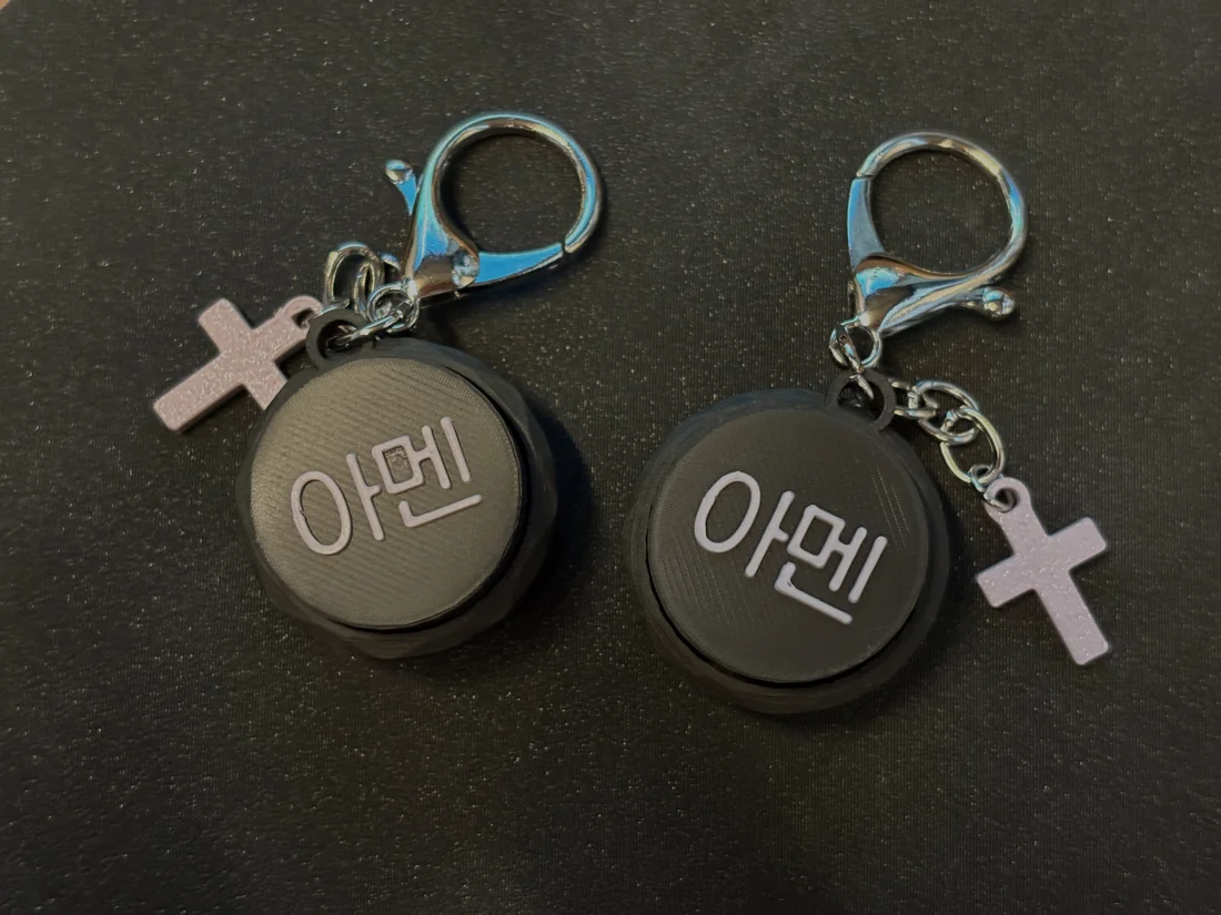 십자가 참과 함께 놓인 아멘 클리커 키링 두 개